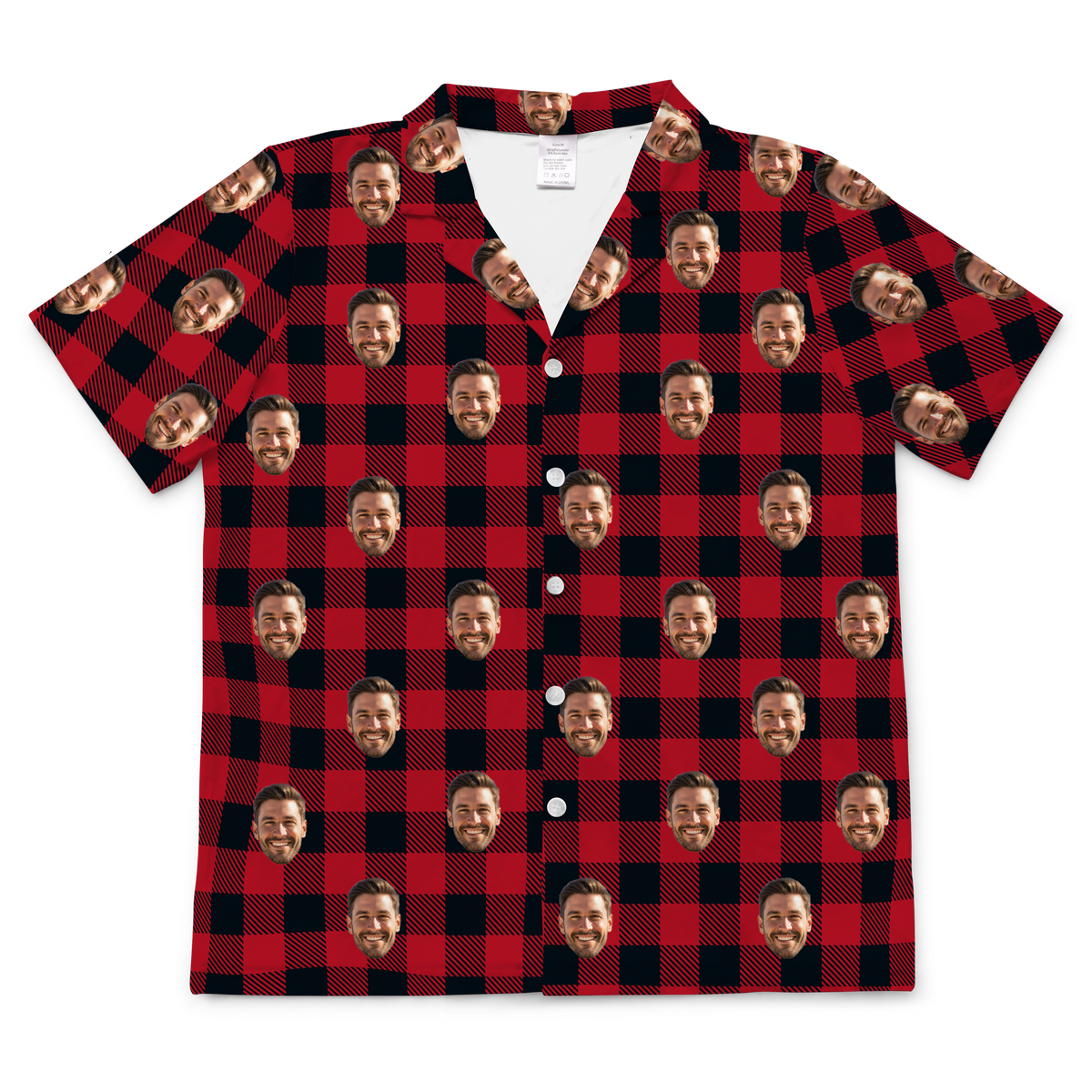 A short-sleeved, button-up pajama or casual shirt featuring a classic red and black buffalo plaid pattern. Repeated headshots of a smiling, bearded man are superimposed onto the plaid fabric.