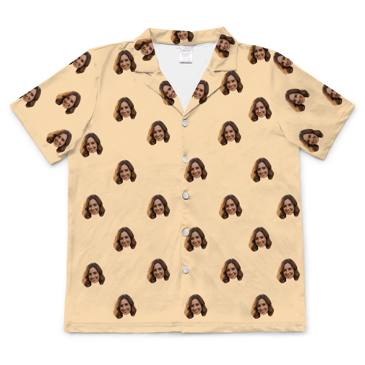 Short-sleeved, button-down pajama top in a solid buttery yellow or pale tan color, featuring a repeating pattern of a smiling woman's face with brown hair.