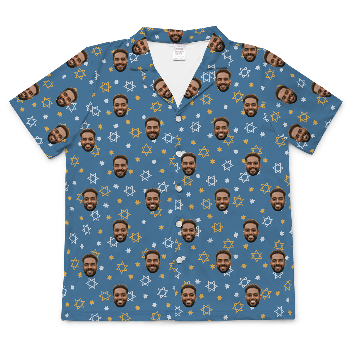 A short-sleeved, button-up pajama or casual shirt featuring a dusty blue background patterned with small white and yellow outlines of the Star of David, along with tiny white dots. Repeated headshots of a smiling, bearded man's face are superimposed onto the pattern. 