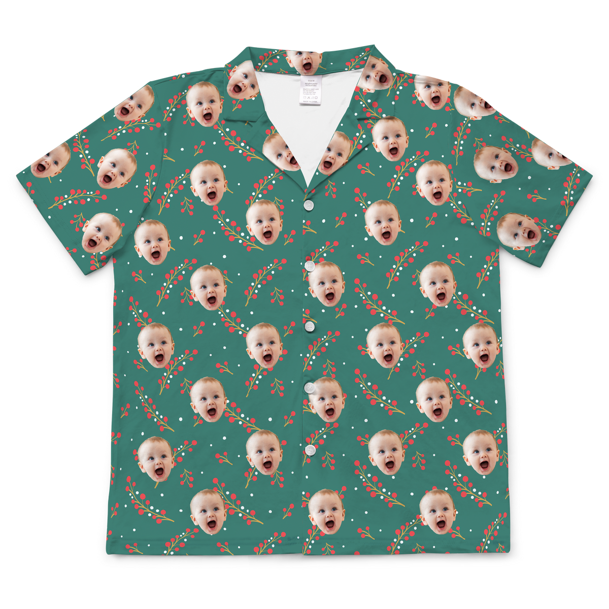 A short-sleeved, button-up pajama or casual shirt featuring a teal background. The fabric is patterned with a festive design of repeating red berries on green stems, along with small white dots.