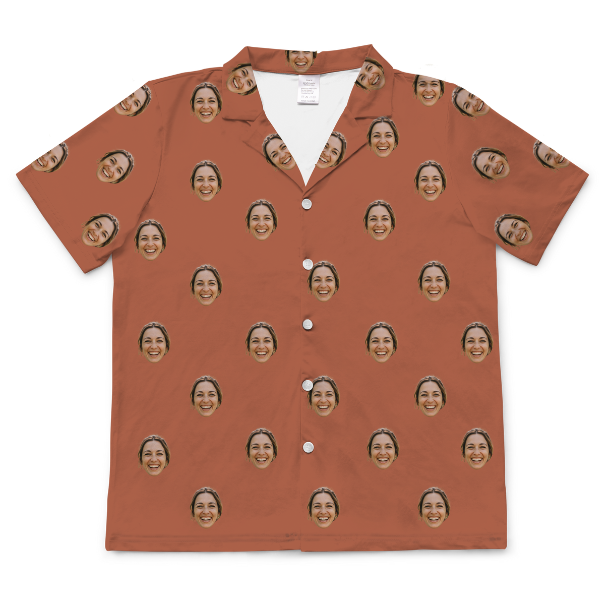 A short-sleeved, button-up pajama or casual shirt in a solid burnt orange or cocoa-colored fabric. Repeated headshots of a smiling woman's face are evenly spaced and superimposed across the fabric.
