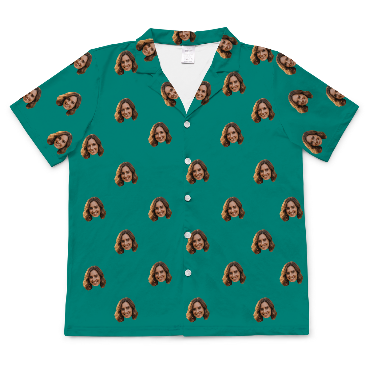 A short-sleeved, button-up pajama or casual shirt in a solid teal or dark turquoise fabric. Repeated headshots of a smiling woman's face are evenly spaced and superimposed across the fabric.