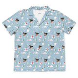 A short-sleeve button-up camp shirt in light blue, featuring an all-over print of dogs wearing winter clothing, snowmen, Christmas trees, and snowflakes.