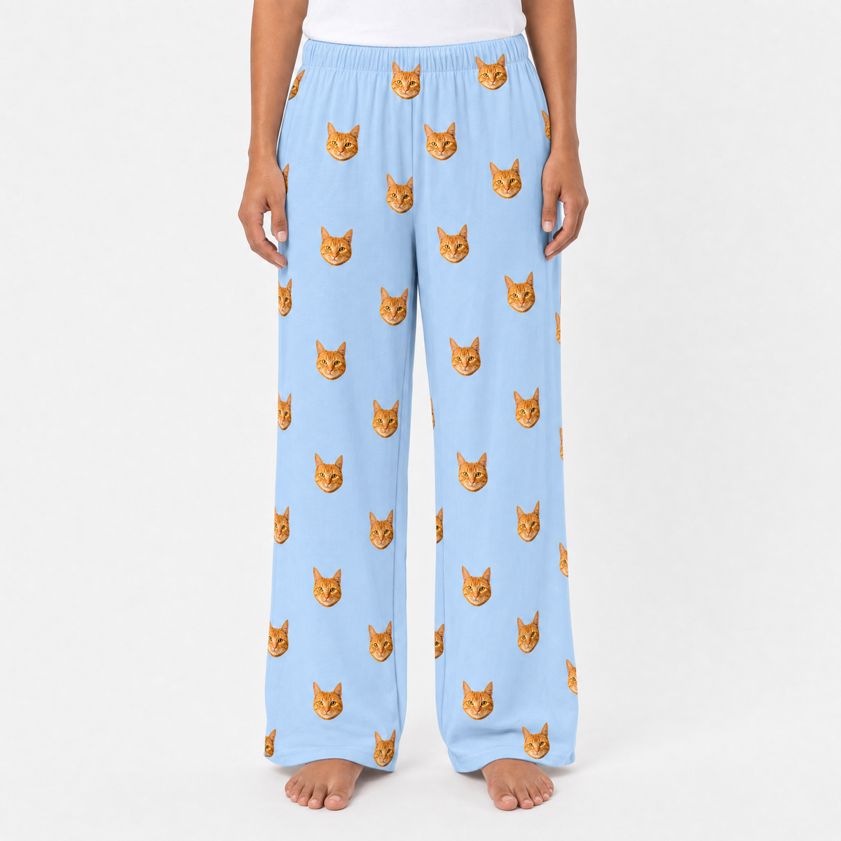 Sky blue pajama pants with cat pattern worn by a person on a white background