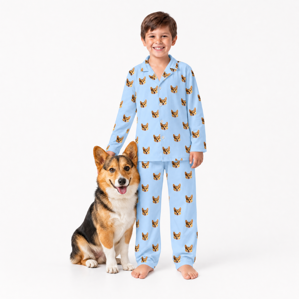 Child wearing sky blue pajamas with dog pattern standing next to a dog on a white background