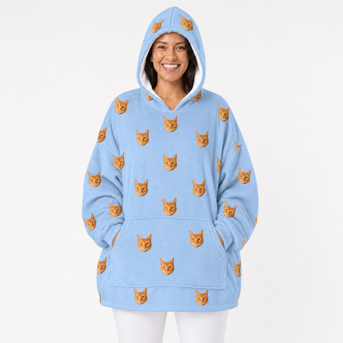 Person wearing a sky blue blanket hoodie with orange cat patterns on a white background