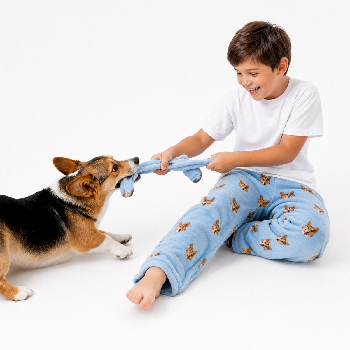 Child playing with a dog using a blue toy on a white background