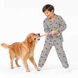 Child in gray pajamas playing tug of war with a dog on a white background