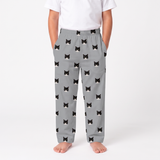 A child wearing slate gray pants with an all-over black and white cat face print, paired with a white t-shirt, shown against a plain white studio background.