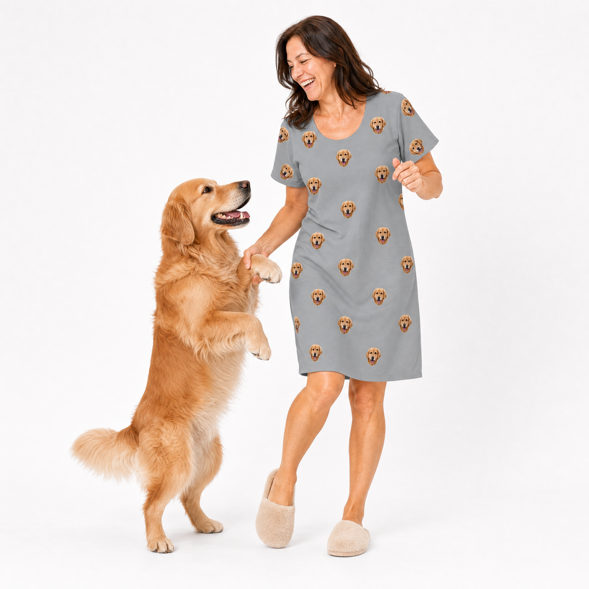 Woman in a gray nightgown with dog pattern interacting with a standing dog on a white background