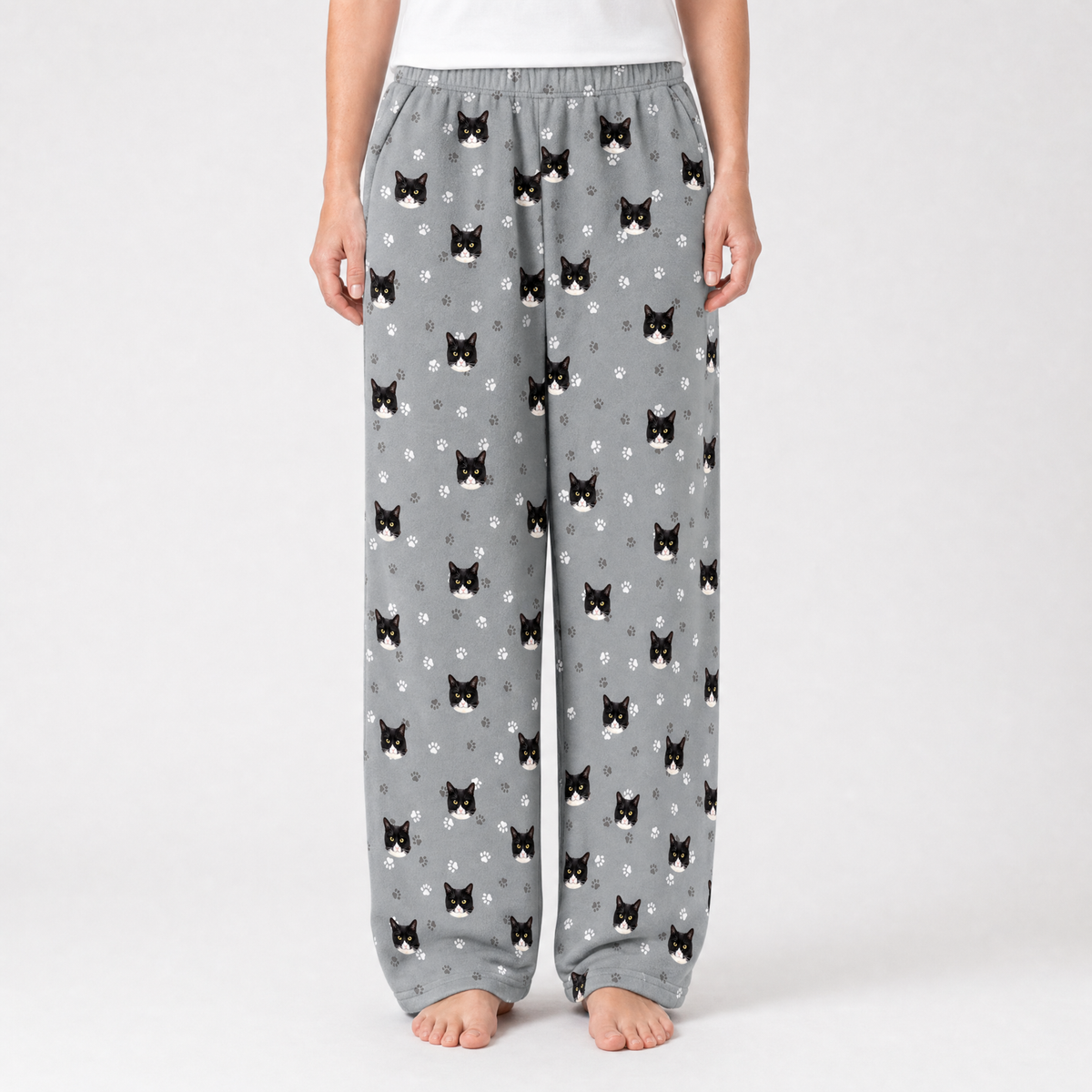 Gray pajama pants with black cat pattern worn by a person on a white background