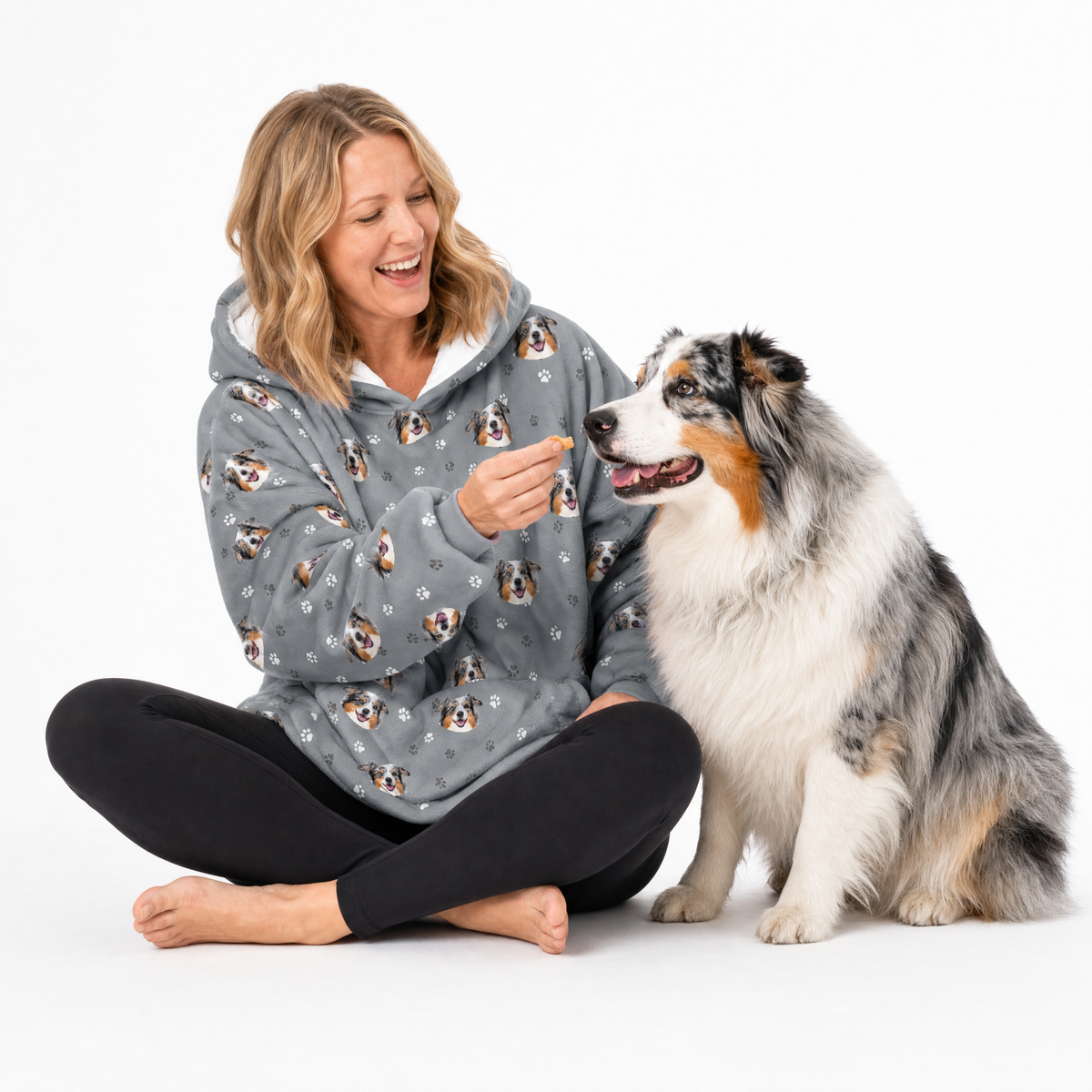 Slate gray paws hoodie theme – person in dog-print hoodie offering treat to Australian Shepherd.