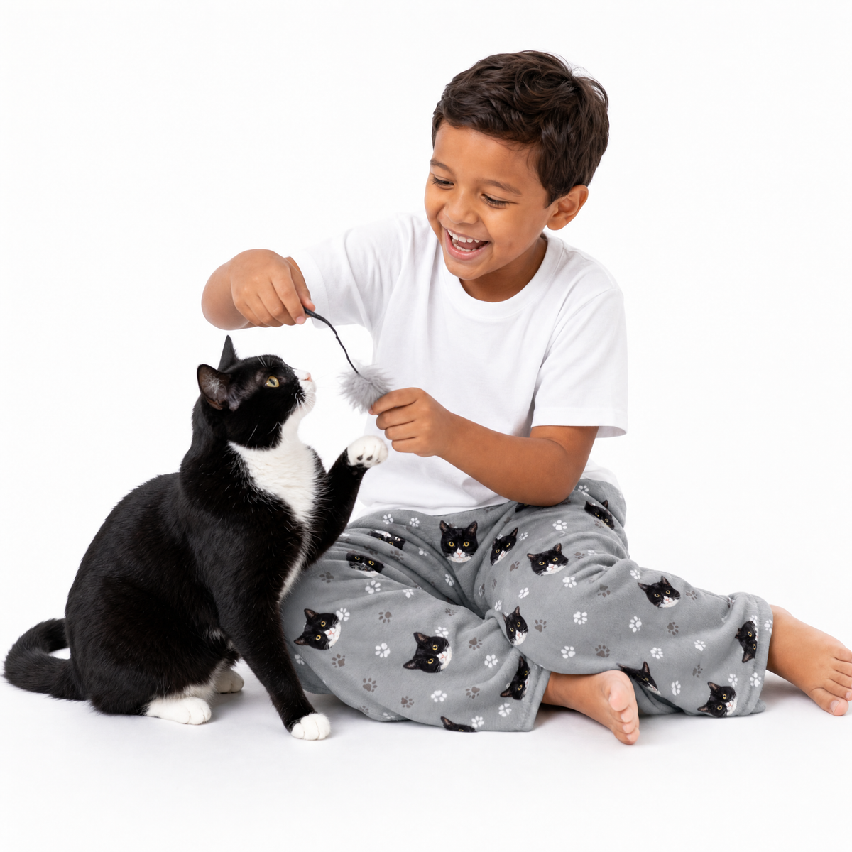 Child playing with a black and white cat on a white background