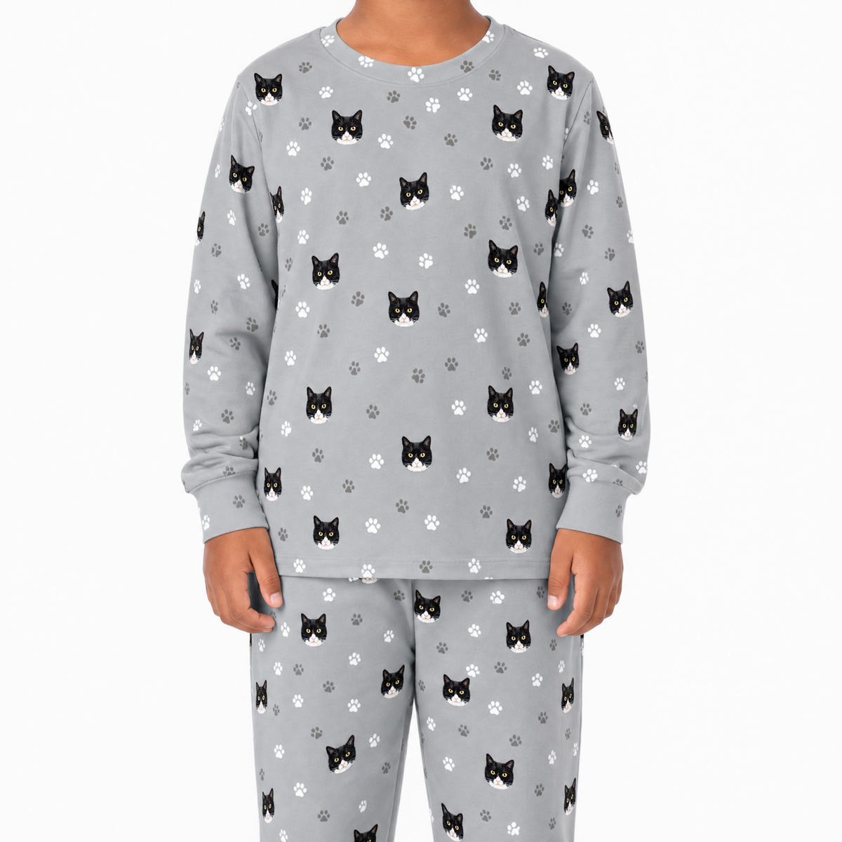 Child wearing gray jogger pajamas with black cat and paw print pattern on a white background