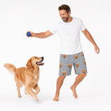 Man playing with a dog wearing gray shorts with dog pattern