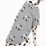 Dalmatian wearing a gray custom dog shirt with a repeating dog face pattern on a white studio background.