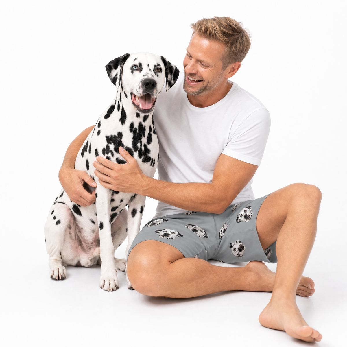 Man in a white t-shirt and gray shorts with a Dalmatian dog on a white background