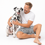 Man in a white t-shirt and gray shorts with a Dalmatian dog on a white background