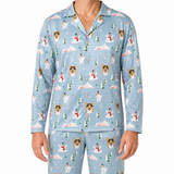 A person wearing a light blue long-sleeve pajama set with an all-over Christmas-themed print featuring dogs, snowmen, trees, mountains, and snowflakes, shown against a plain white background.