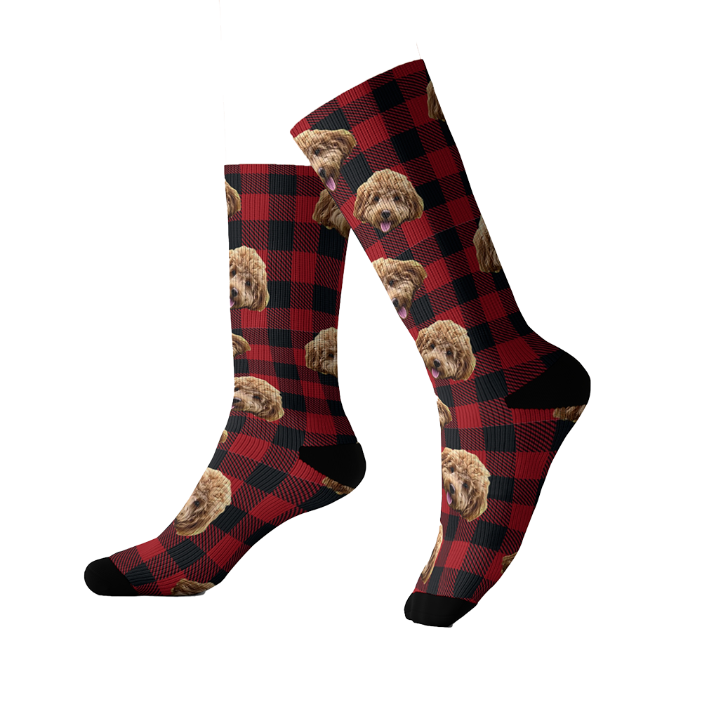 Red and black buffalo plaid socks featuring a repeating pattern of a fluffy brown dog’s face. The socks have black toes and heels.