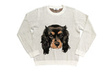 A light beige knit crewneck sweater featuring a large graphic print of a black and tan dog's face on the front, displayed flat against a white background.