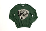 A dark green crewneck sweatshirt featuring a detailed graphic of a curly-haired dog's face in black and white on the front, laid flat against a white background.