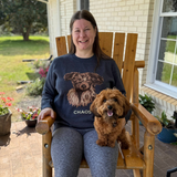 Woman with dog on lap, wearing knit sweater with dog design and text.