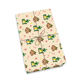 A rectangular gift box wrapped in cream-colored paper with a festive pattern of green elves, brown cookies, and candy canes, tied with a simple brown string on a white background.[WrappingPaper_IconicElf]