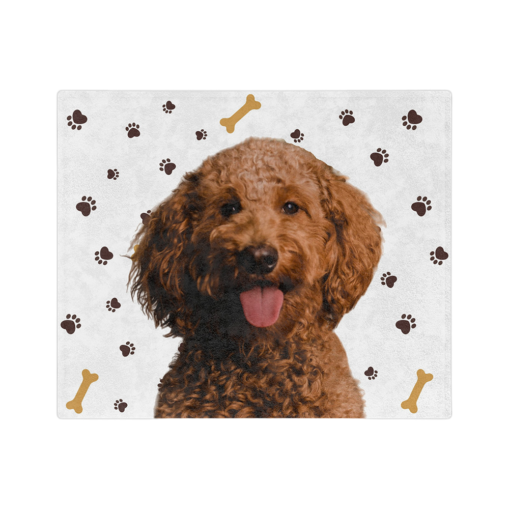 A blanket with a white background and paw prints, featuring a centered, smiling portrait of a dog.