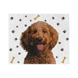A blanket with a white background and paw prints, featuring a centered, smiling portrait of a dog.