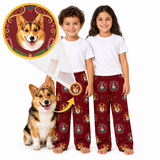 Two children and a corgi wearing matching burgundy pajama pants with a repeating dog-face print, shown on a white studio background. A circular inset at upper left shows a close-up of the print design.
