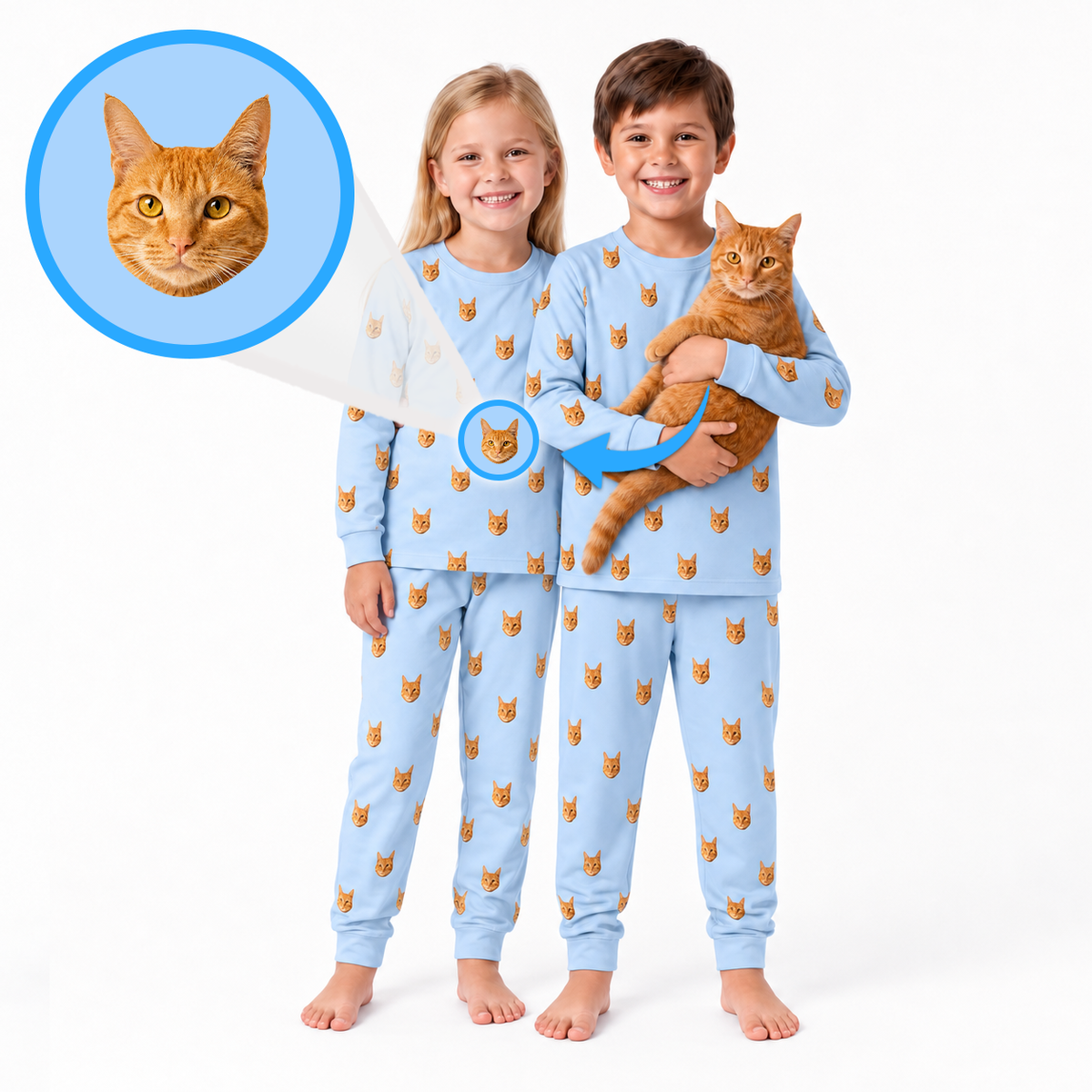 Two children wearing light blue pajamas with a repeating orange tabby cat face print, standing barefoot on a white studio background. One child holds an orange tabby cat, and a circular inset at the top left shows a close-up of the cat face pattern.