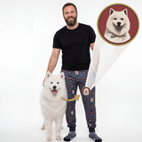 A man wearing dark patterned pajama pants stands next to a white Samoyed dog on a white studio background. A circular inset at the top right shows a white dog portrait, with an arrow pointing to the man's pant leg, indicating the product is custom pet portrait pajamas.