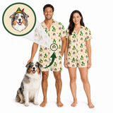 A man and a woman wearing matching custom-printed pajamas stand barefoot on a white studio background next to a dog. The pajamas have a light cream base with a repeating print of small dogs in green hats, and the top left shows a circular inset of the custom dog portrait with an arrow pointing to the print.