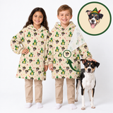 Two children wearing matching hooded sweatshirts with a festive Elf on the Shelf print, standing next to a dog, with a circular inset showing a dog illustration wearing the same hat.