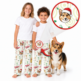Two children wearing matching white pajama tops and Christmas-themed corgi print pants, standing barefoot on a white background next to a corgi dog. A circular inset shows a close-up of the printed corgi face with a Santa hat, and red arrows point to the children's pants to highlight the personalized design.