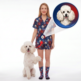 A woman stands on a white studio background wearing a matching short-sleeve pajama set and socks with a dog print, next to a small white poodle. A circular inset at the top right shows a close-up of the poodle, and an arrow points from the print on the clothing to the inset, indicating the product design.