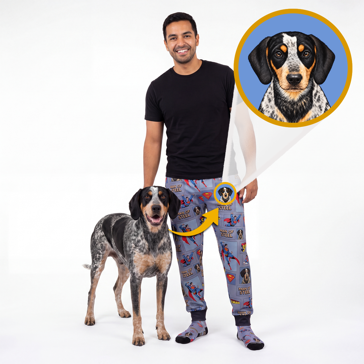 A man and a blue merle dog stand on a white studio background wearing matching custom pet apparel. The man wears gray patterned sweatpants with a dog graphic, and the dog wears matching dog-print socks.
