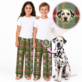 Two children wearing matching green plaid pajama pants with a Dalmatian dog face pattern, standing barefoot next to a Dalmatian dog. An inset circle at the top right shows a close-up of the dog face pattern on the plaid fabric.