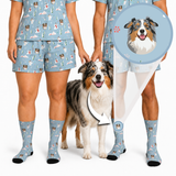 Two people wearing matching light blue custom pet-print pajama sets and socks stand beside an Australian Shepherd. A magnified callout highlights the dog’s illustrated face featured in the personalized print.