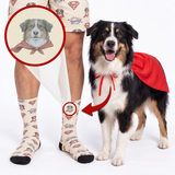 A dog wearing a red cape stands beside a person's legs showing matching patterned socks and shorts. The socks and shorts have a beige base with a repeating superhero-style dog print, and the dog's head is shown enlarged in a circular inset with a red arrow pointing to the matching sock on the person.