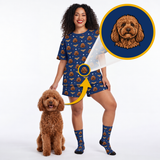 A woman modeling a matching navy blue pajama set with a brown dog print, standing next to a small brown poodle. A circular inset shows a close-up of the dog print design.