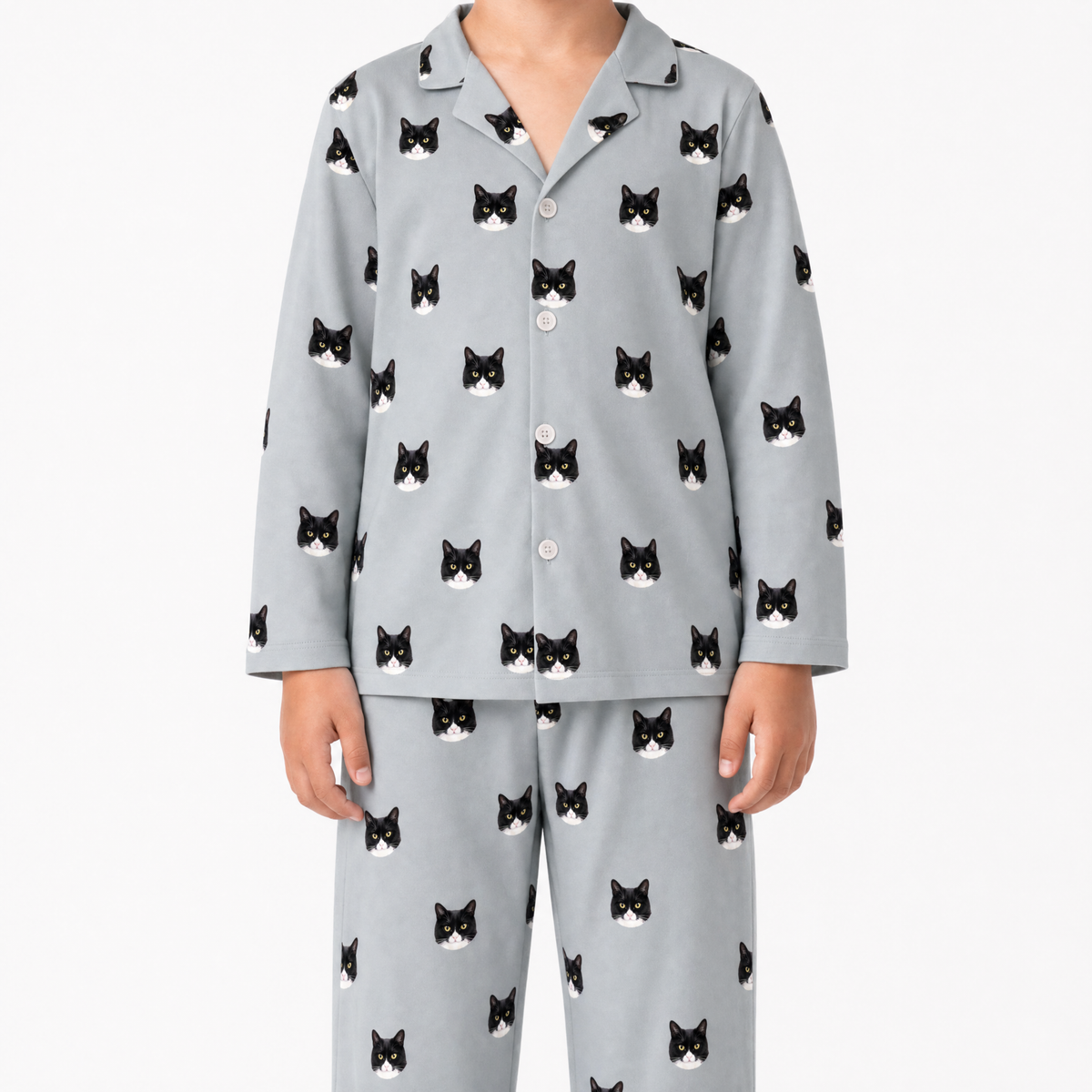 Child wearing gray pajamas with black cat patterns on a white background