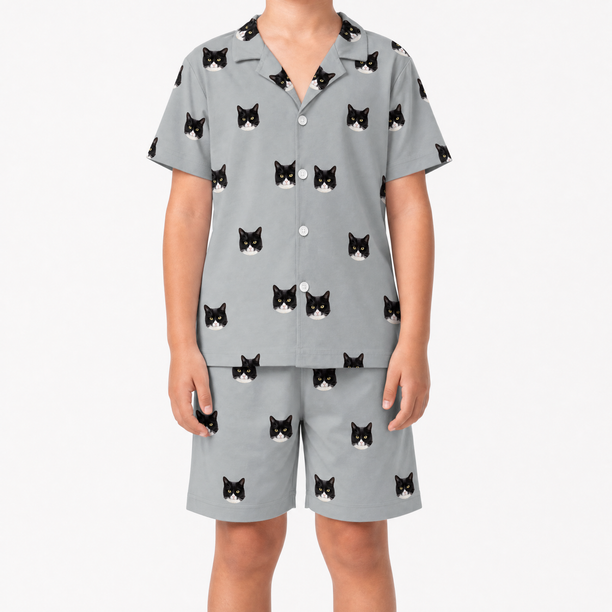Child wearing a gray pajama set with black cat prints on a white background