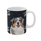 Close up of a black ceramic mug with paws and the phrase "I Love Dad", featuring a smiling, multicolored Australian Shepherd