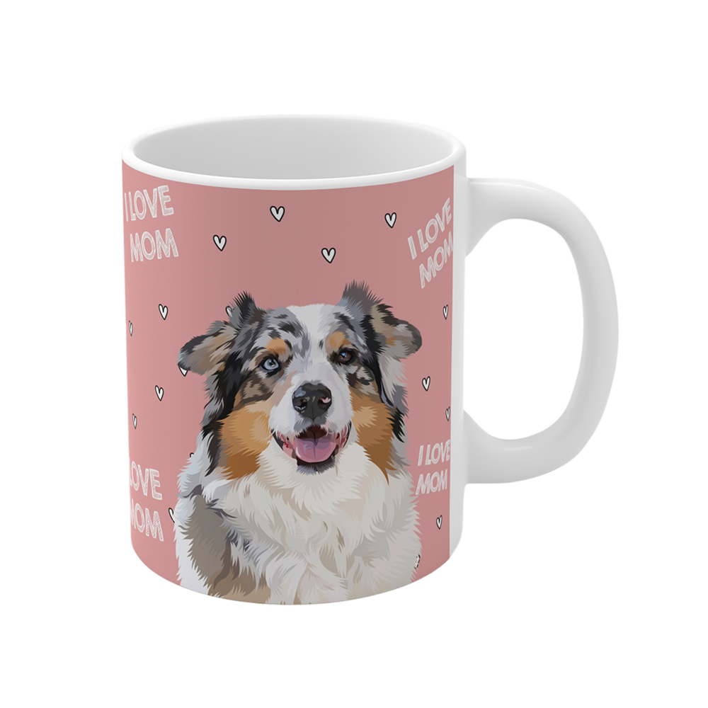 Clos up of a pink ceramic mug with hearts and the phrase "I Love Mom", featuring a smiling, multicolored Australian Shepherd