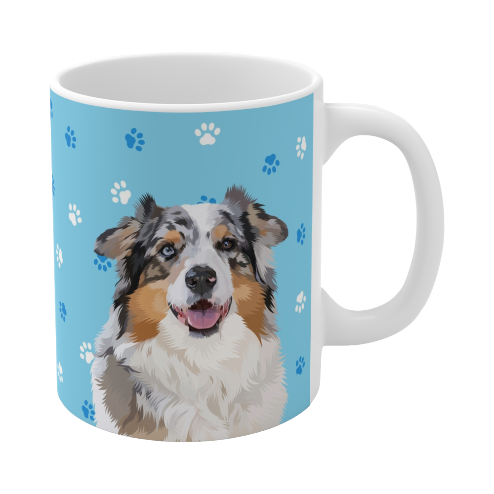 Close up of light blue ceramic mug with paws pattern, featuring a smiling, multicolored Australian Shepherd