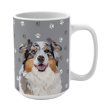 Close up of gray ceramic mug with paws pattern, featuring a smiling, multicolored Australian Shepherd