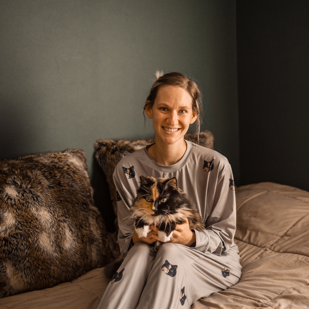 Lady wearing a gray sleeping outfit with her cat