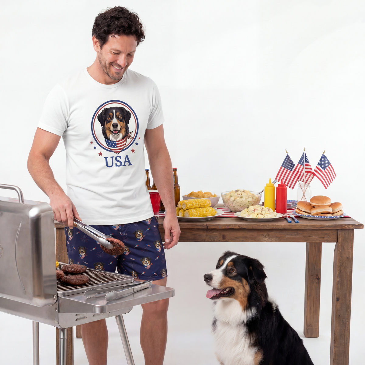 Man grilling outdoors with a dog, table with food, and American flags in the background